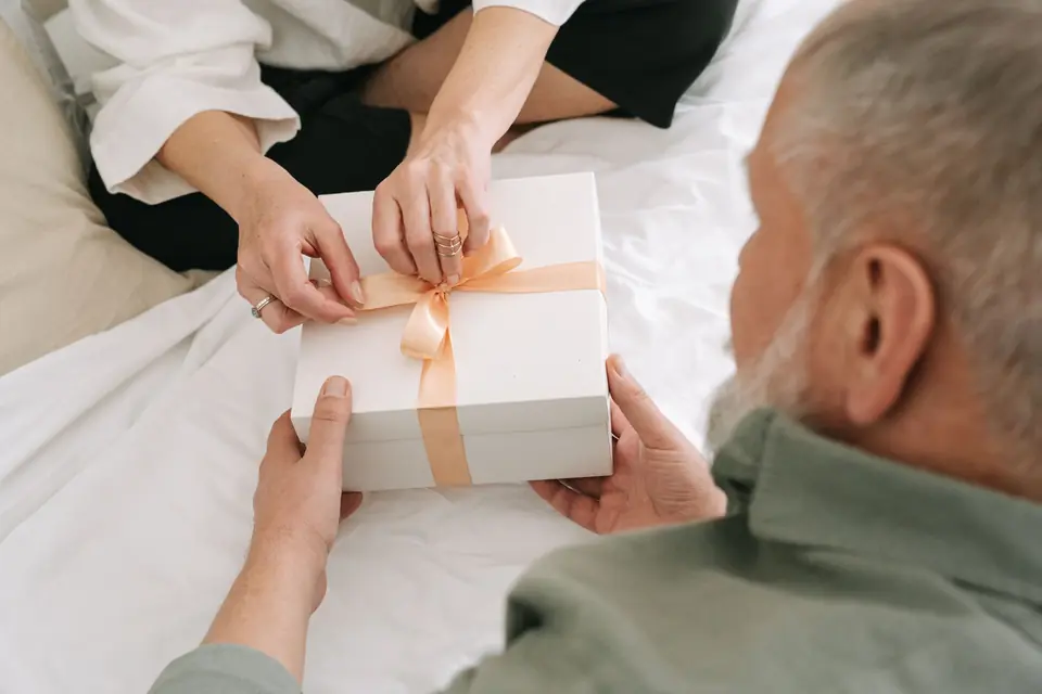 An older couple exchanging a wrapped anniversary gift