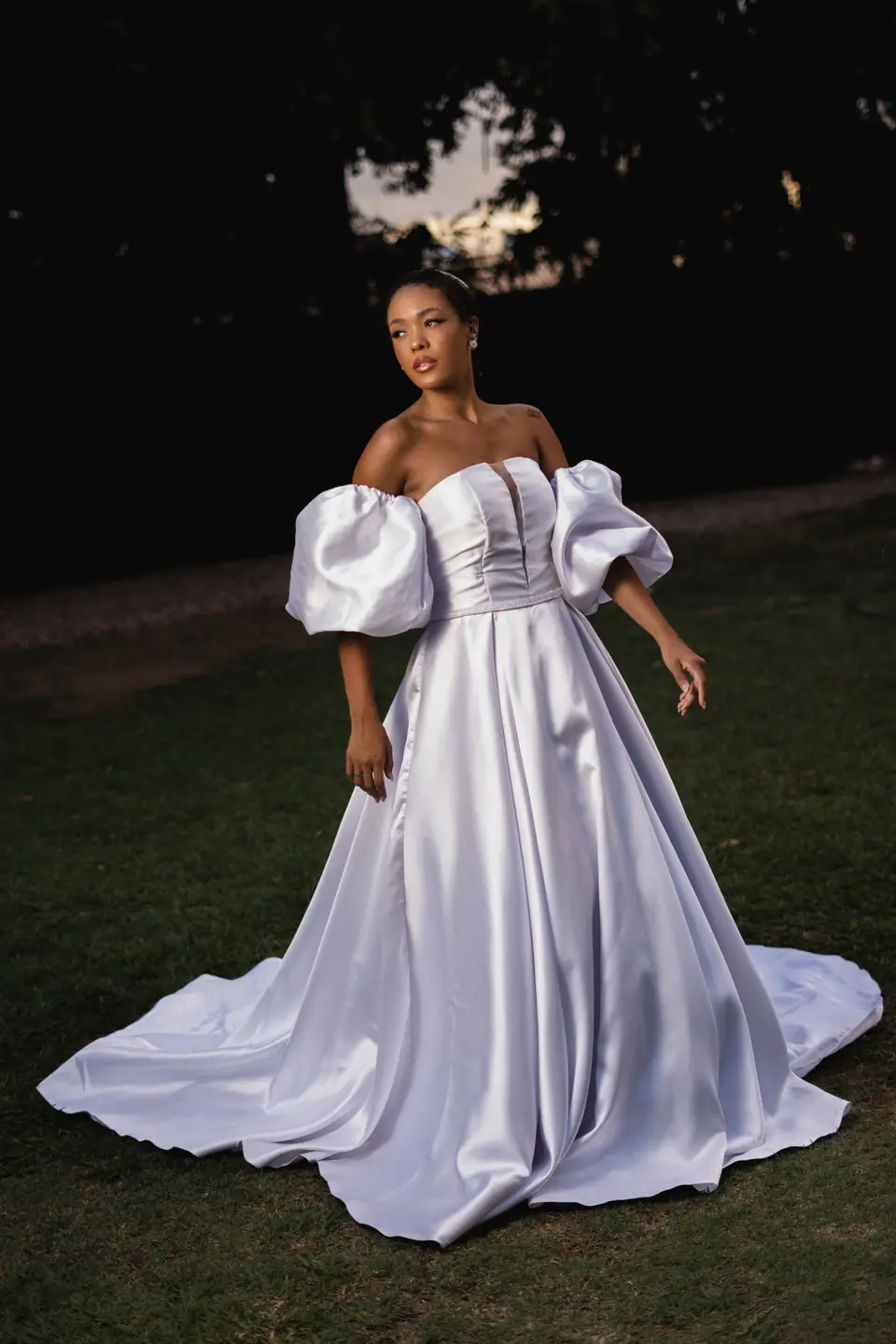 A bride in a satin ball gown with puff sleeves at night