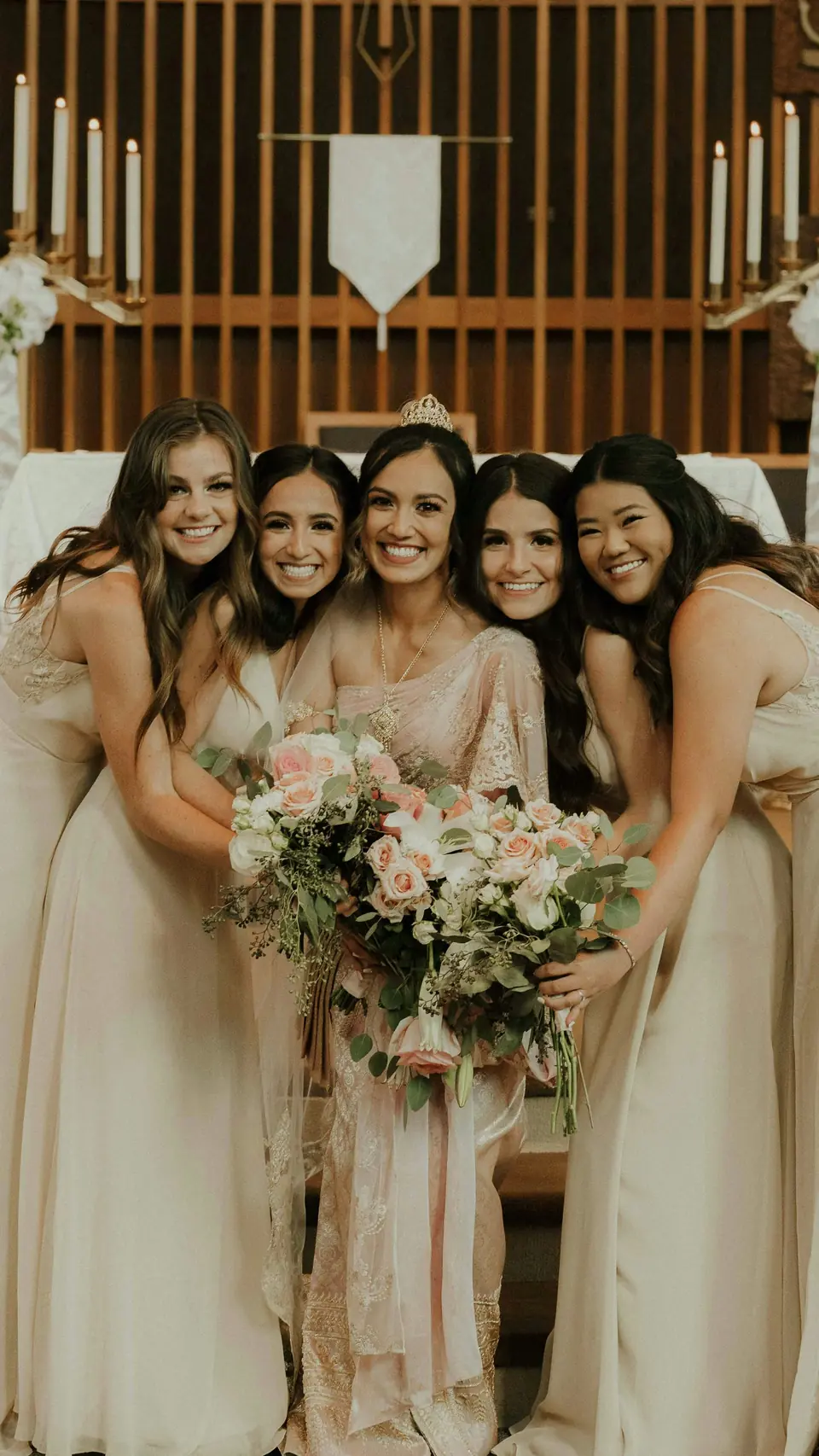 A bride laughing with her bridesmaids in champagne dresses