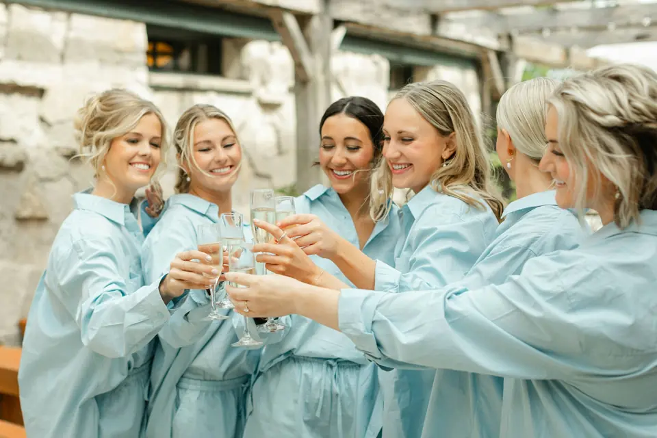 Bridesmaids in matching robes toasting while getting ready