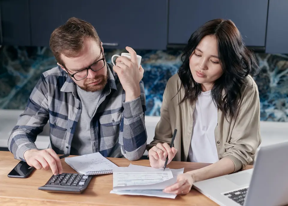 A couple working through bills and a budget with a calculator