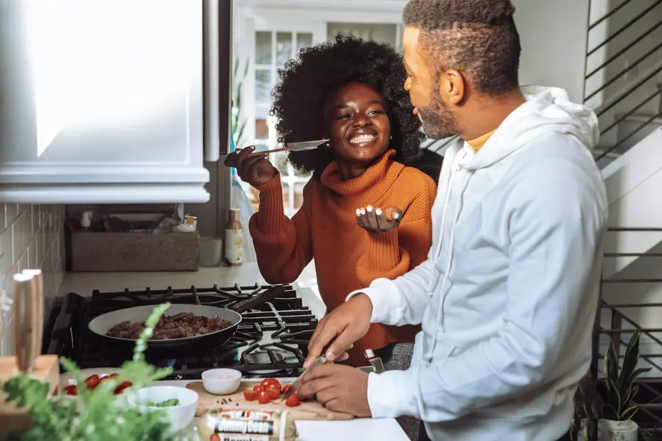 A couple laughing while cooking together at home