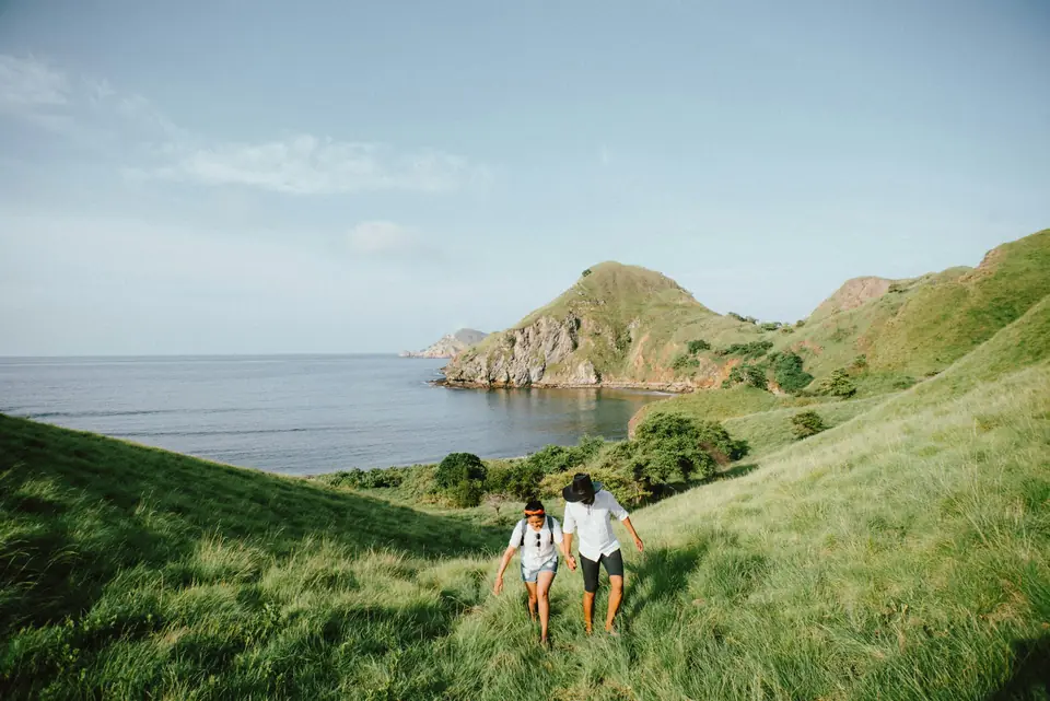 A couple hiking along green hills above the sea