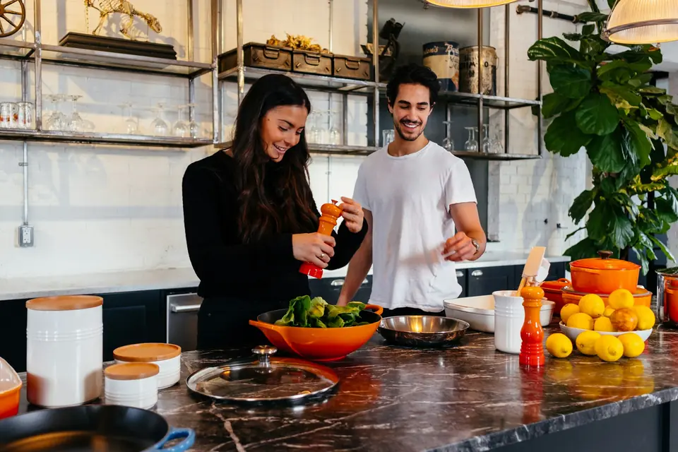 A couple cooking together in a sunny kitchen