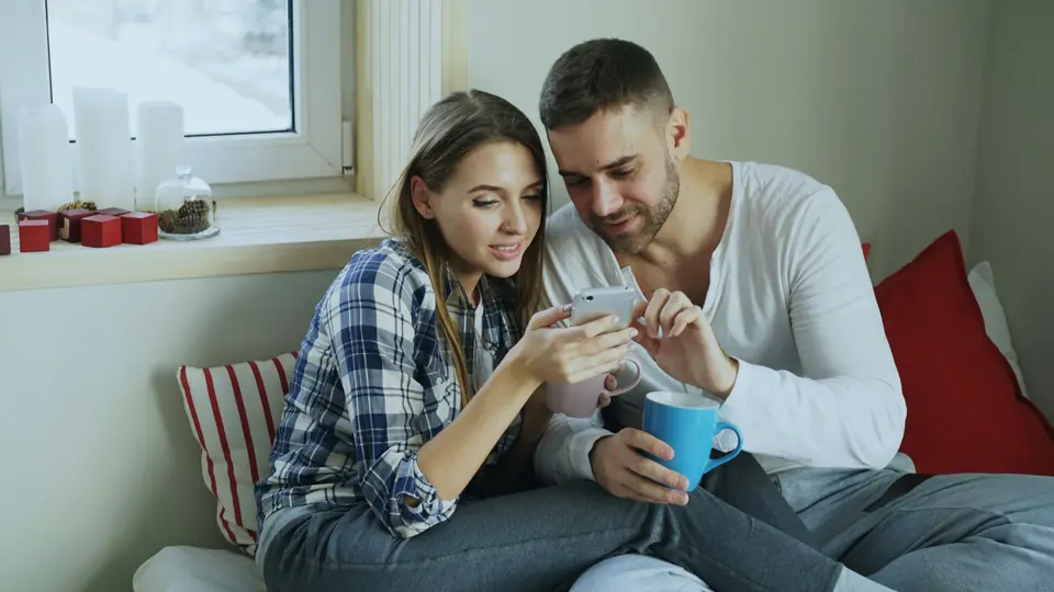 A young couple on a sofa looking at a phone together