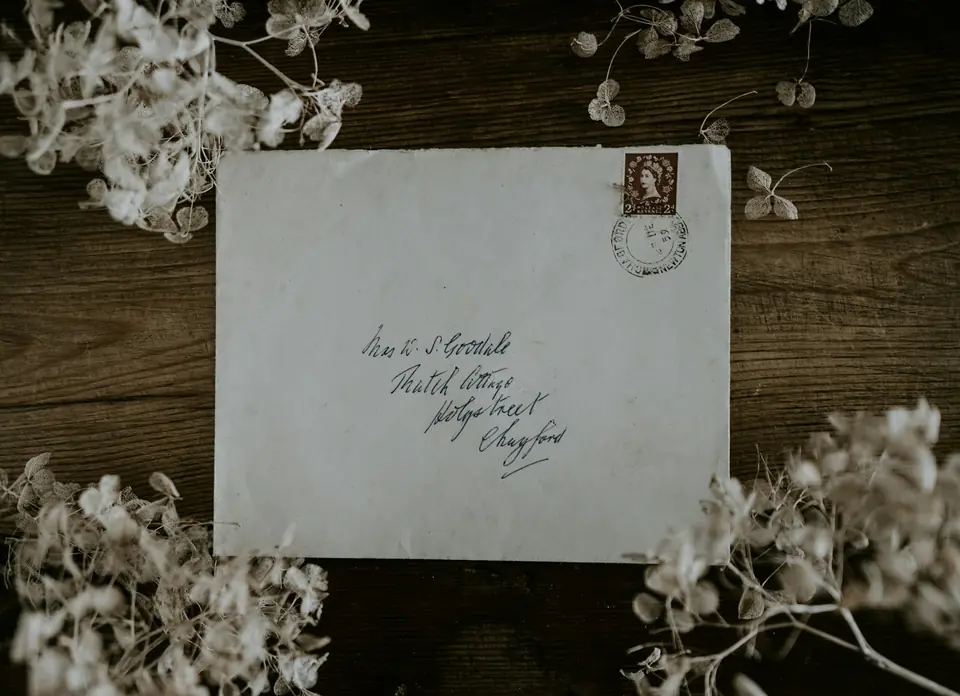 A hand-addressed envelope with dried flowers on a dark wooden table