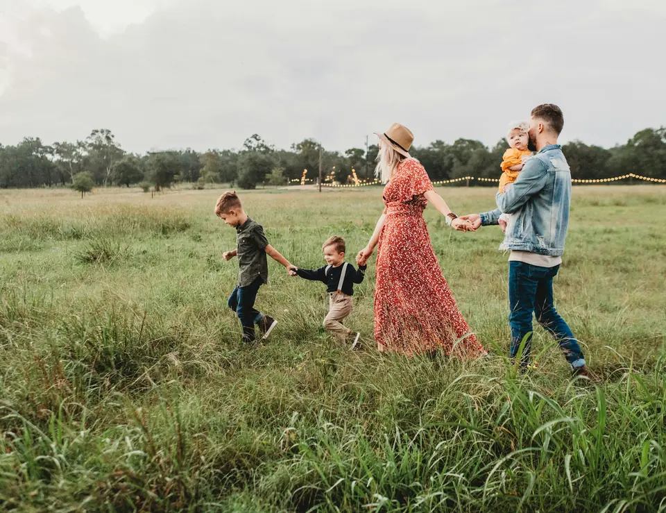 A family walking through a meadow with their young children