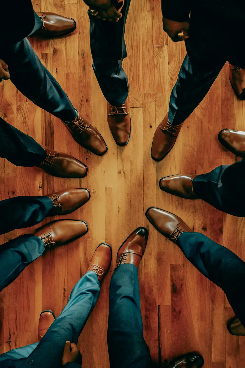 The groomsmen's polished shoes arranged in a circle on a wooden floor
