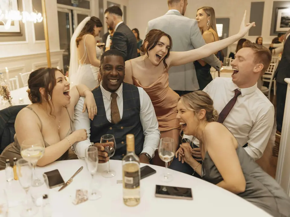 Wedding guests laughing together around a reception table
