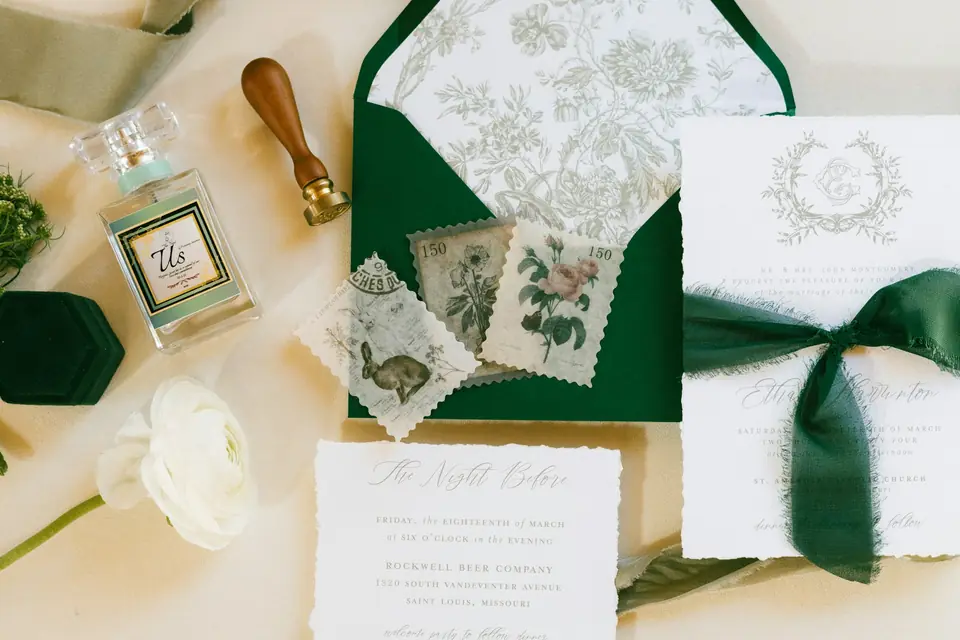 An invitation suite with a green velvet ribbon, wax seal and white roses