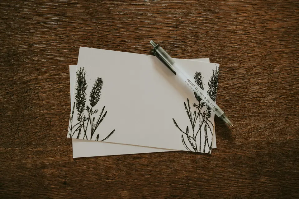 Blank notecards and a pen on a wooden desk