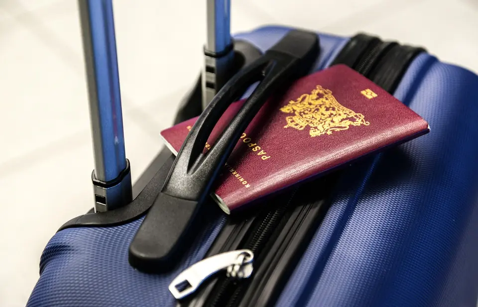 A passport tucked into the handle of a blue suitcase