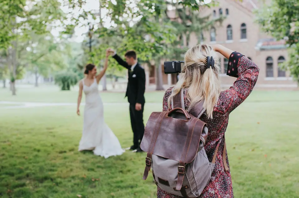 A wedding photographer photographing a couple on a lawn