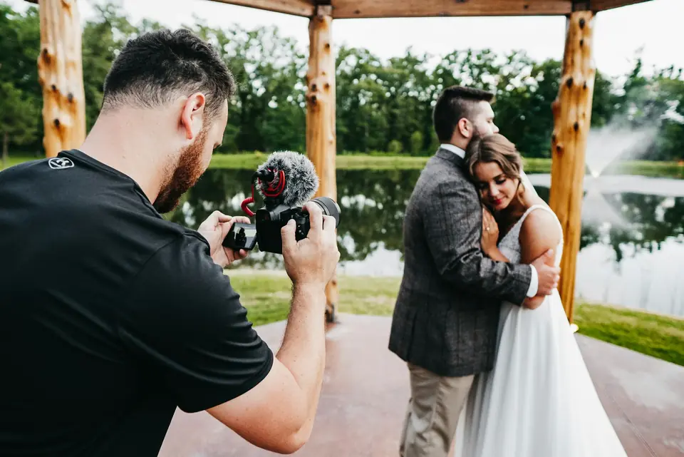 A photographer capturing a couple embracing under a pergola
