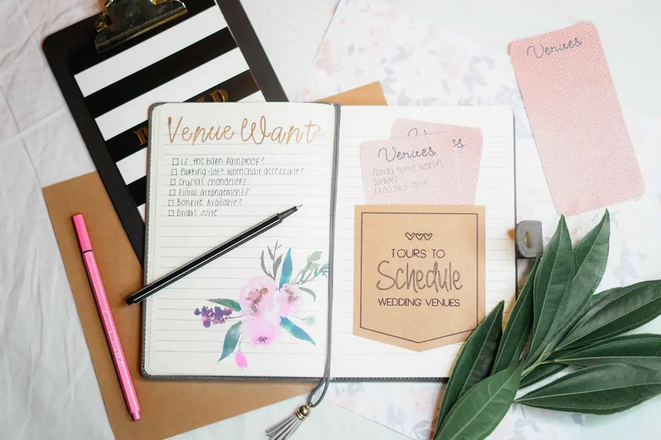 A pastel planning notebook with venue notes, a pen and stationery