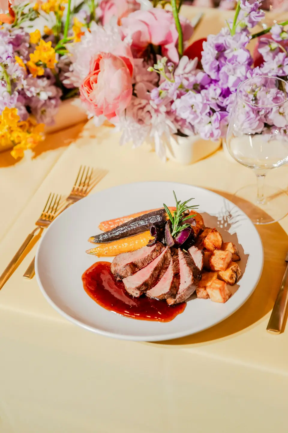 A plated wedding main course beneath bright table flowers