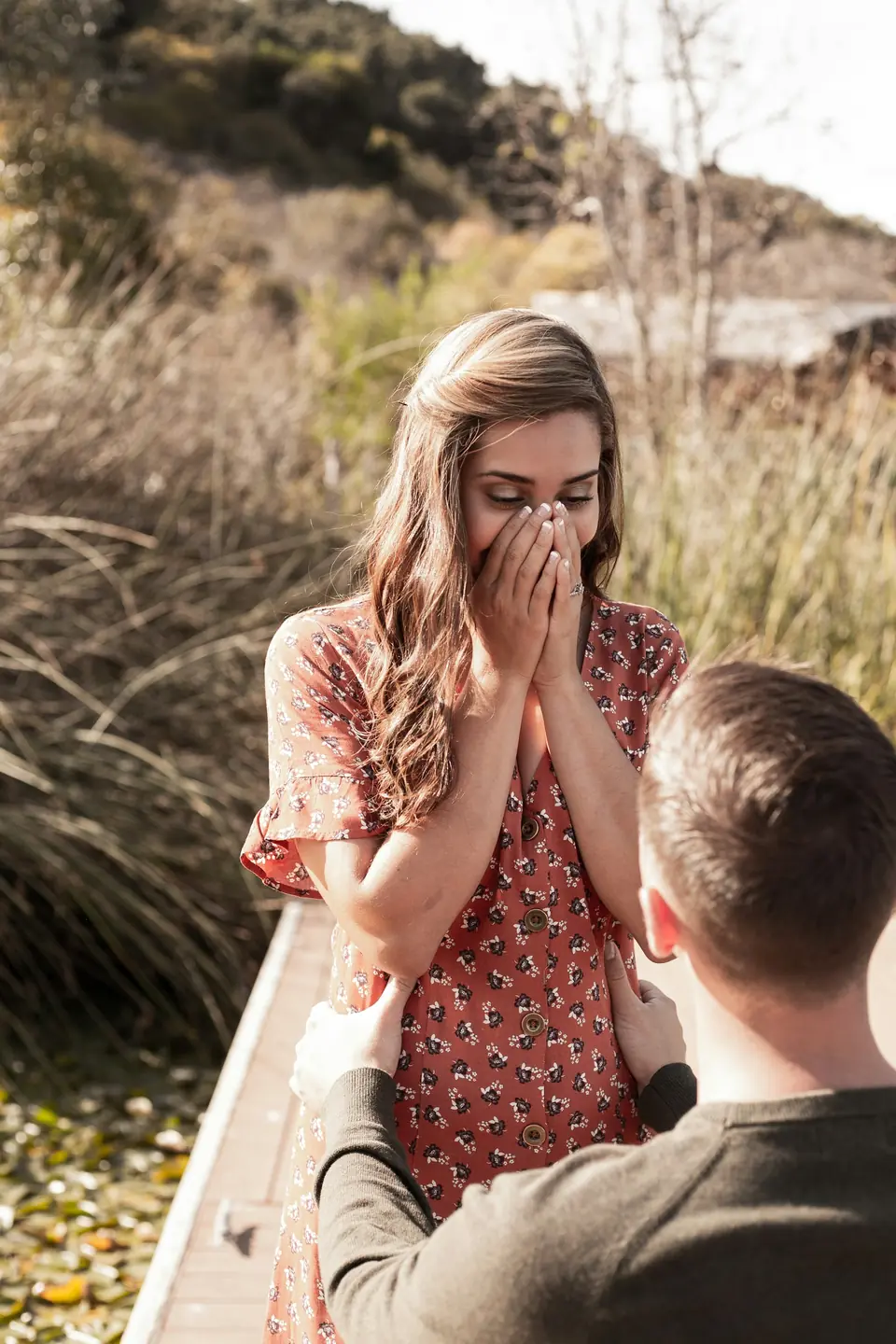 A woman covering her mouth in surprise as her partner proposes