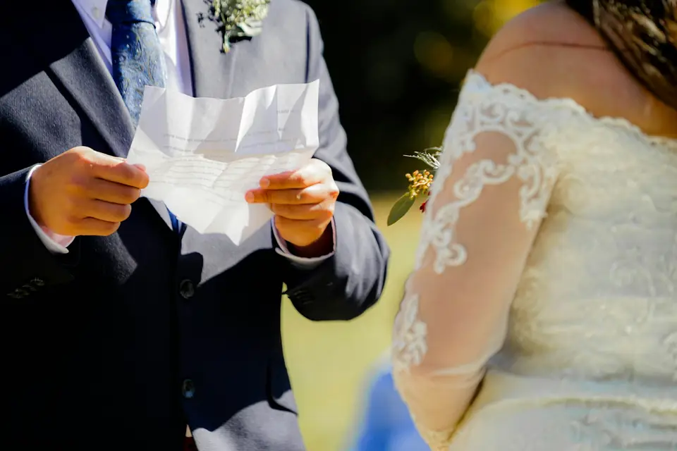 A groom reading handwritten vows to his bride