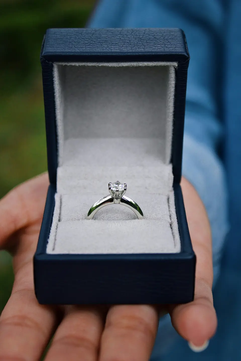 A solitaire engagement ring in an open navy ring box
