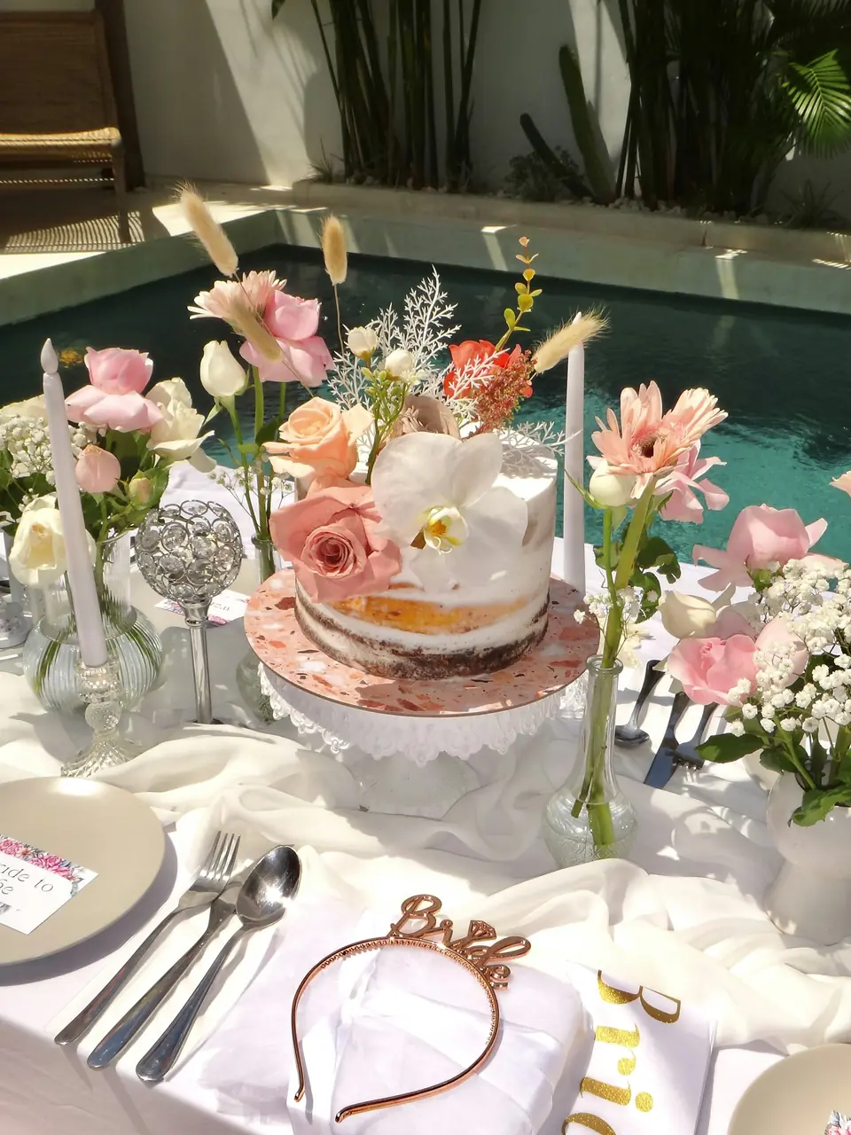 A bridal shower table with cake, flowers and a bride headband